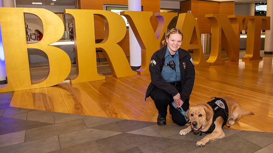Sarah Sirois and Archie pose in front of the large, yellow Bryant letters.